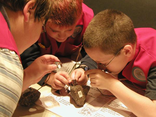 three children examine a rock sample